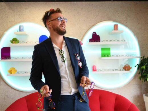 Un homme en costume marine sourit, locataire des lunettes. La boutique sur mesure est à Carcassonne.